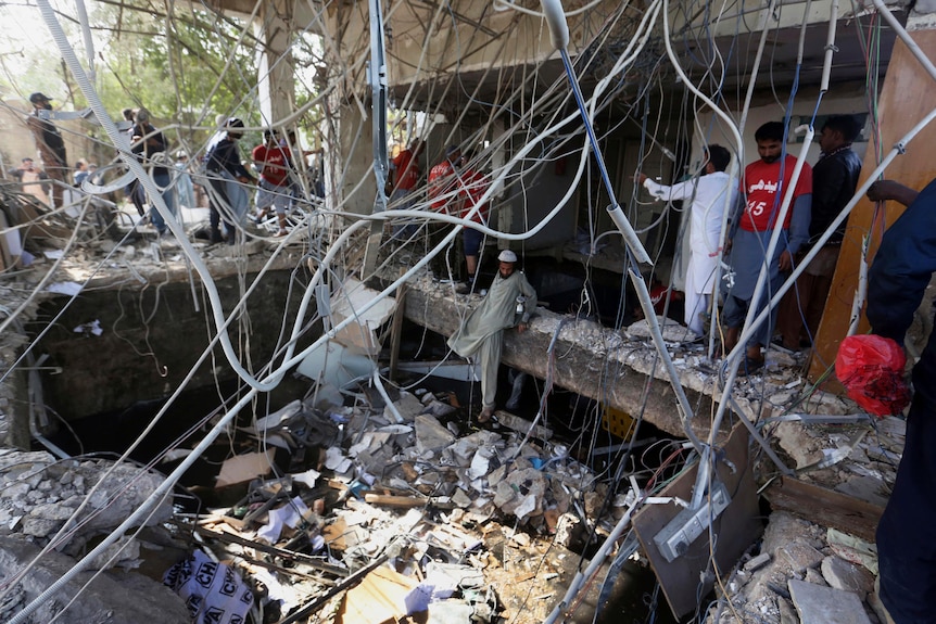 Rescuers inspect the scene of a gas explosion, the floor caved in inside the building.