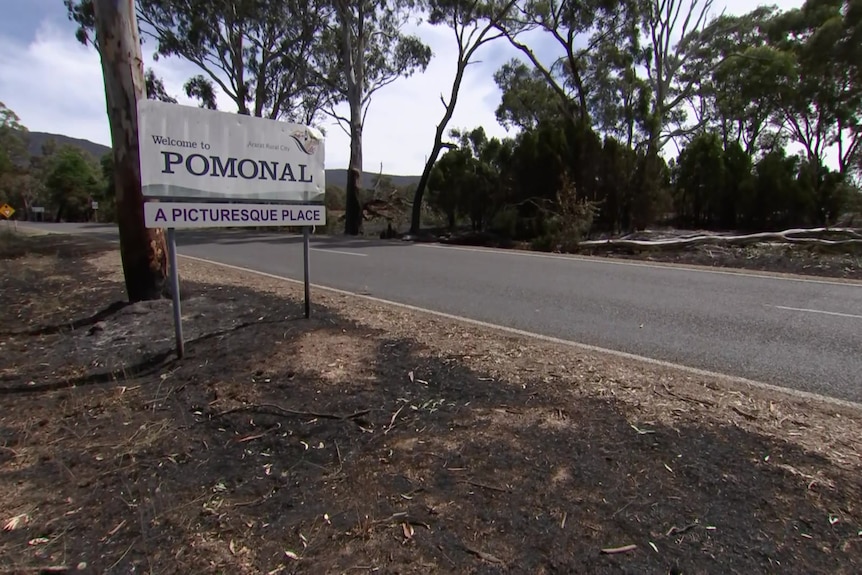 A welcome to Pomonal sign on burnt out ground. 