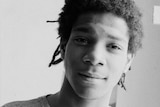 Black and white portrait of New York artist Jean-Michel Basquiat, his face half lit and half in shadow.