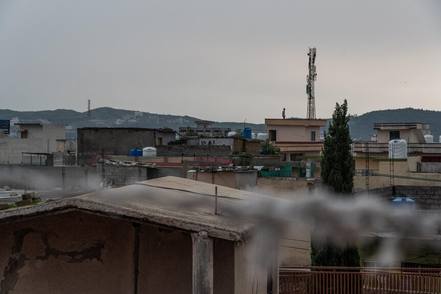 The Islamabad skyline shows cement rooftops and a mountain range in the background. 