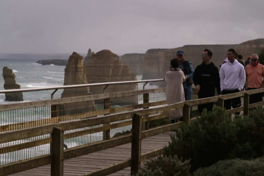 Tourists at a viewing platform looking out over rocky outcrops near the Great Ocean Road.
