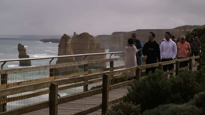 Tourists at a viewing platform looking out over rocky outcrops near the Great Ocean Road.