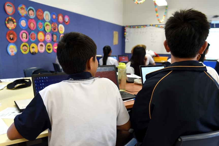 The back of two boys' heads as they sit in a classroom.