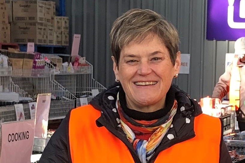 Sarah Pennell is in a Foodbank distribution centre and is wearing an orange vest