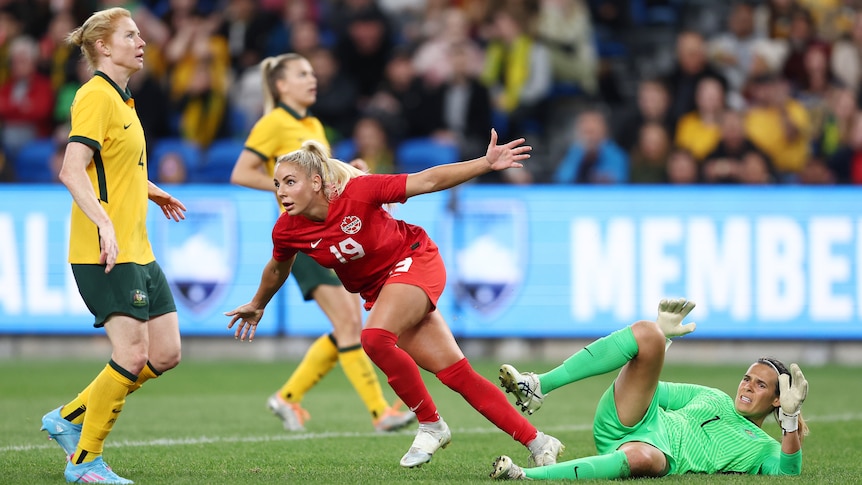 A woman soccer player wearing red celebrates after scoring