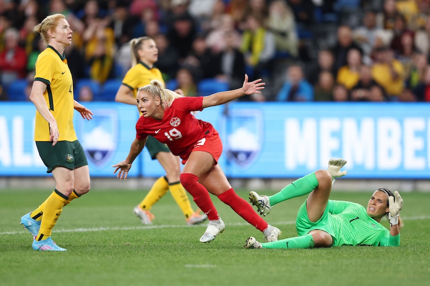 A woman soccer player wearing red celebrates after scoring