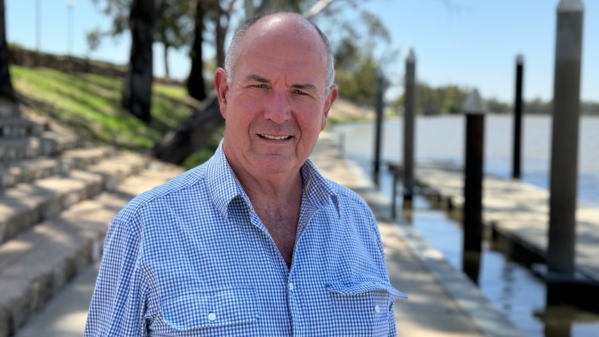A balding, middle-aged, fair-skinnned man, Charles, stands on a wharf at Berri waterfront on the River Murray.