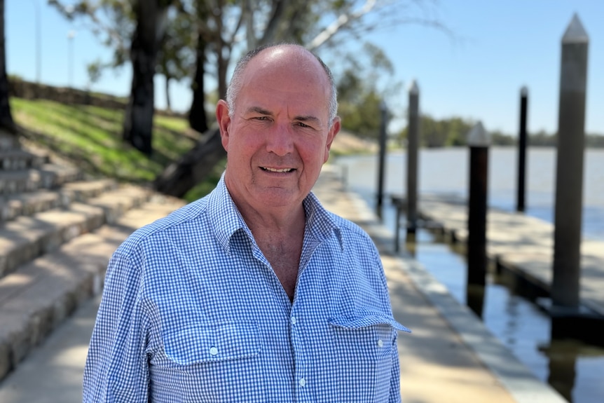 A balding, middle-aged, fair-skinnned man, Charles, stands on a wharf at Berri waterfront on the River Murray.