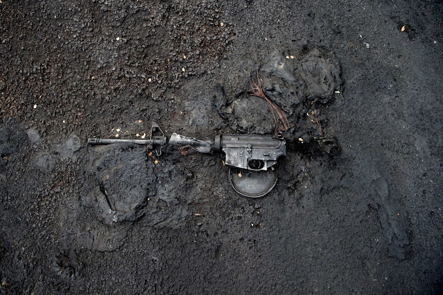 The remains of a rifle are seen melted into a street
