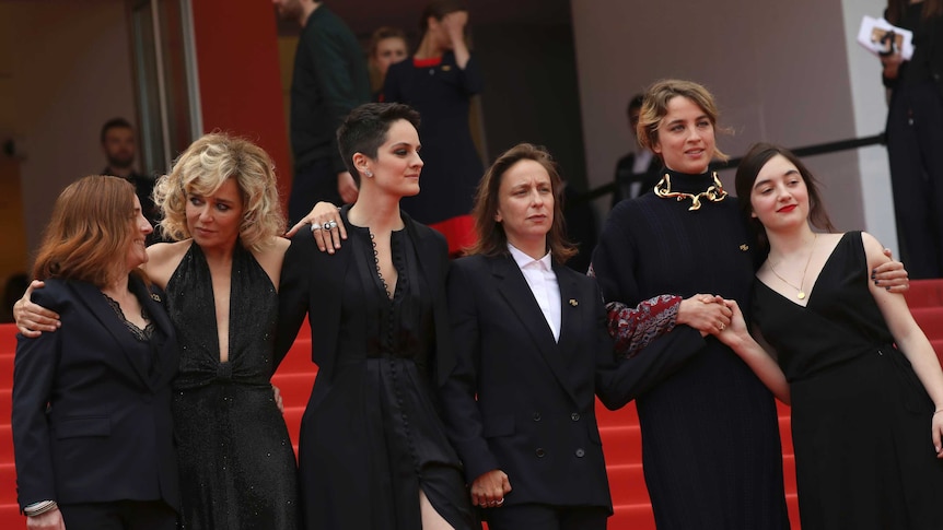 A group of women in formalwear pose for photographers on the red carpet at Cannes.
