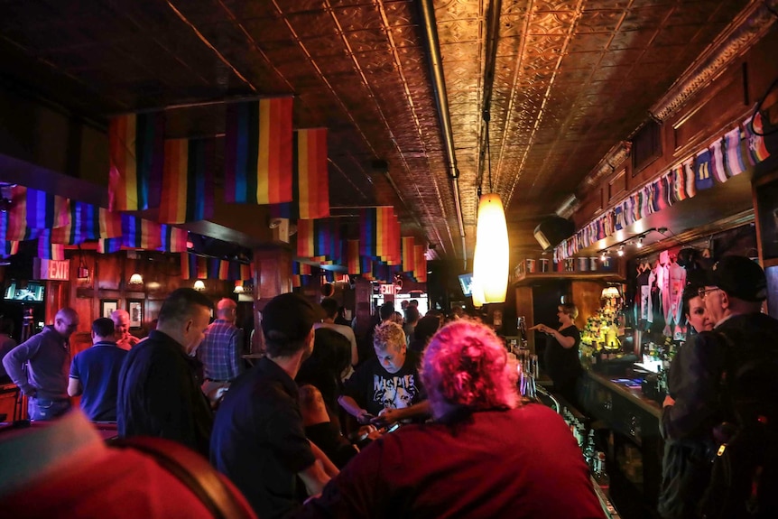 Dozens of people are inside the Stonewall In bar, which is darkly lit