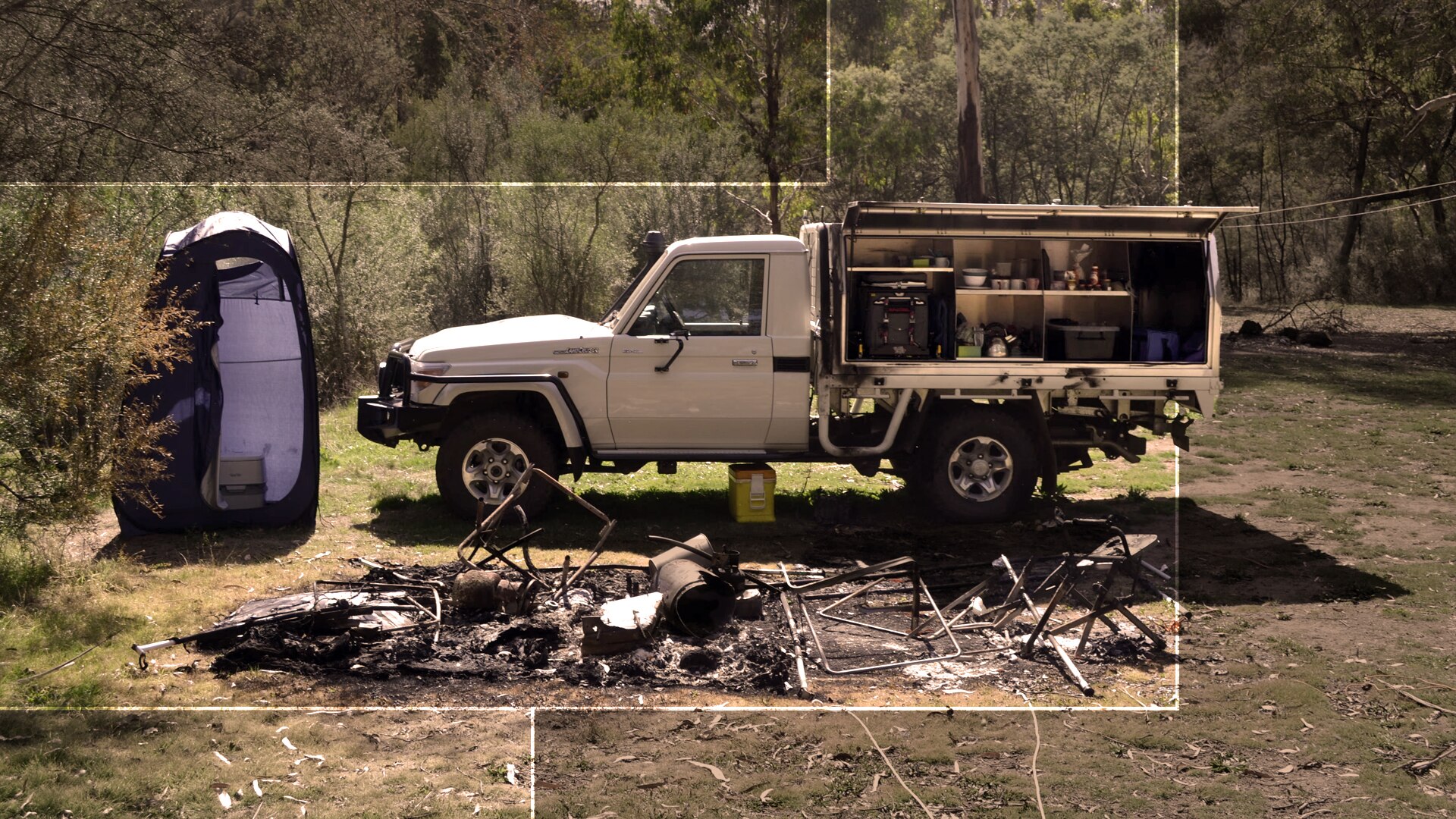 A car next to the burnt-out remains of a tent.