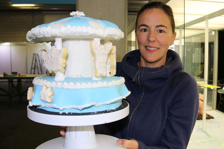 A woman holding a carousel cake