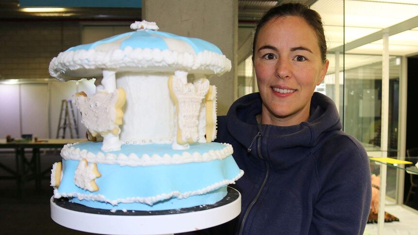 A woman holding a carousel cake