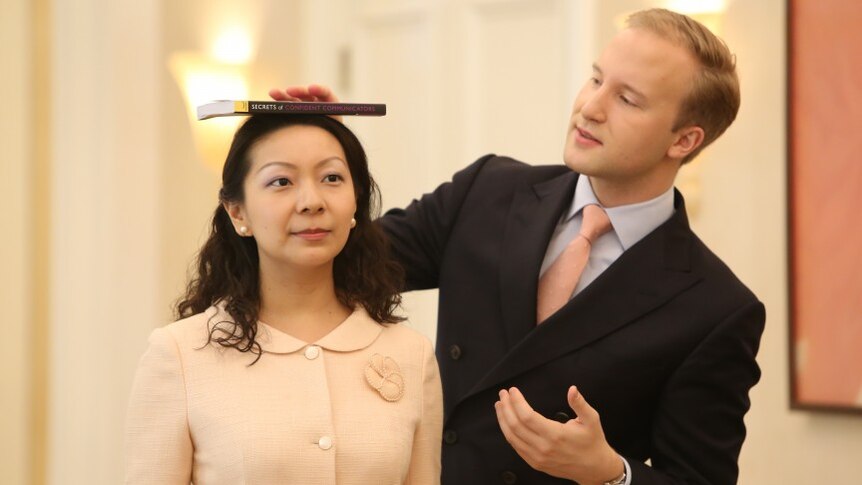 William Hanson holds a book on top of a woman's head