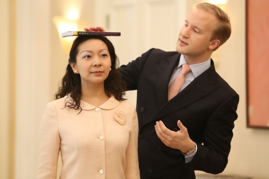 William Hanson holds a book on top of a woman's head