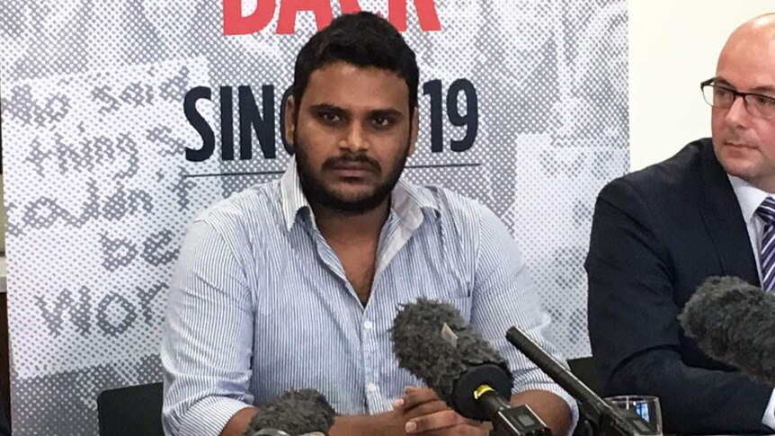 A 7-Eleven worker facing microphones at a media conference in Brisbane