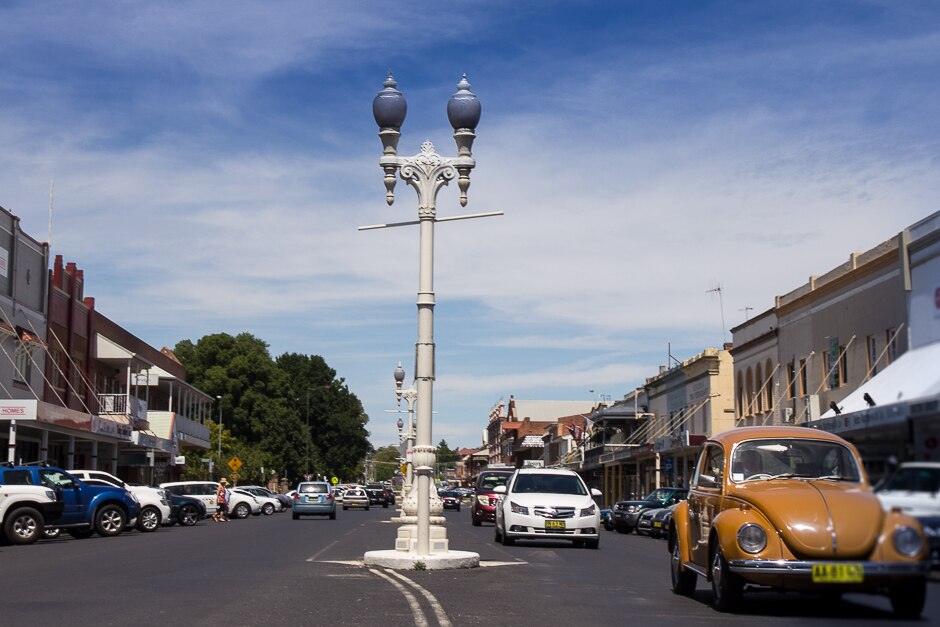 Ornate 1920s street lamps in a street with cars driving by