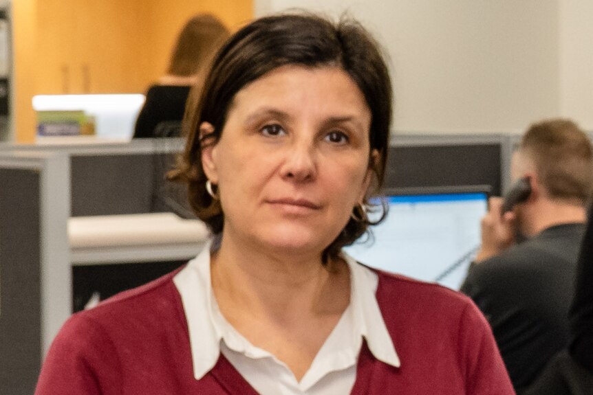 A woman wearing a cardigan looking at the camera