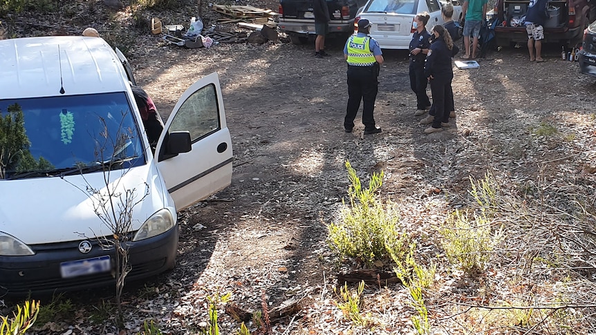 Police and rangers stand surrounded by cars