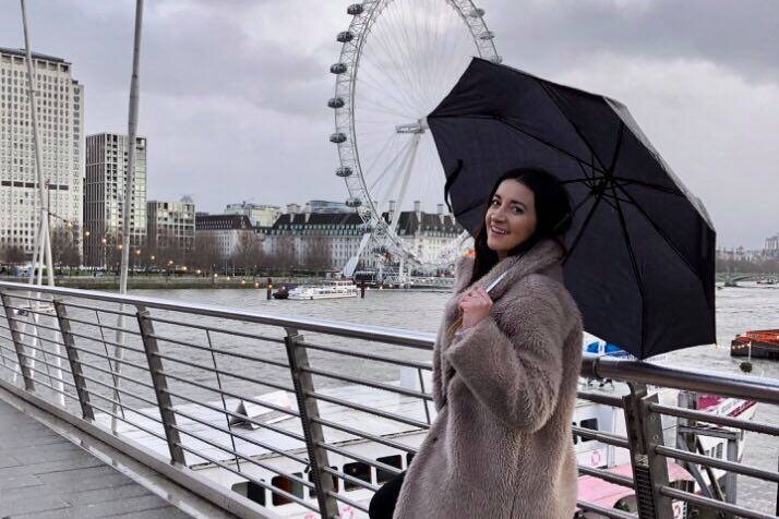 Lauren Potts tient un parapluie sur un pont près du London Eye.