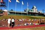 Two people lay flowers outside Dreamworld