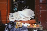 A homeless person sleeping in a doorway on the street