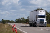 Truck travels down regional road.