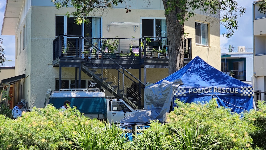Police tent and truck are set up outside a two storey unit block 