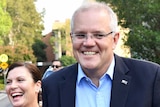 Morrison and his wife grin as they approach the media outside church