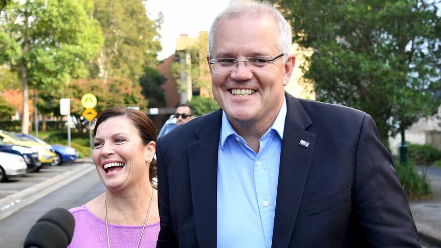 Morrison and his wife grin as they approach the media outside church