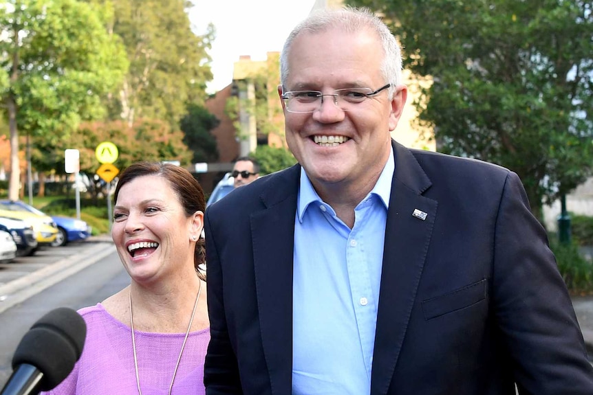 Morrison and his wife grin as they approach the media outside church