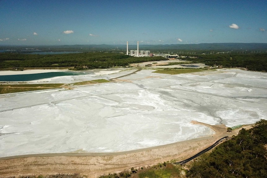 A dam covered in ash with a power station next to it