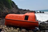 Orange lifeboat washes up on island shore in Indonesia.