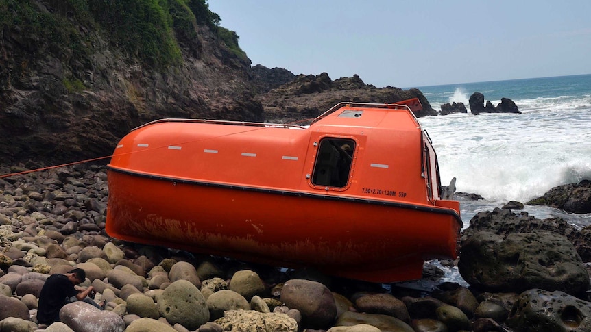 Orange lifeboat washes up on island shore in Indonesia.