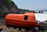 Orange lifeboat washes up on island shore in Indonesia.
