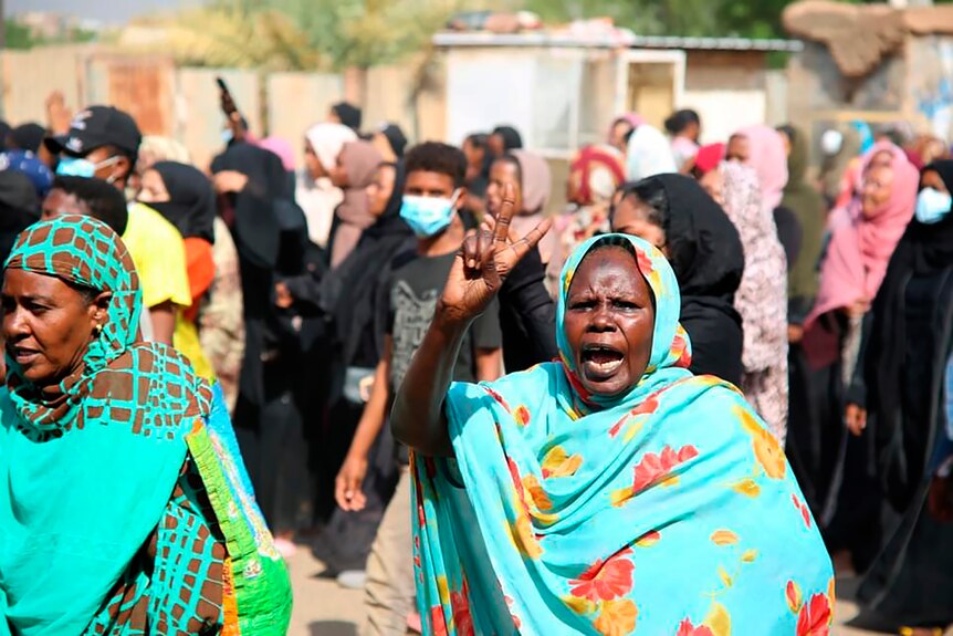 A woman in Sudan in a headscarf flashing a peace sign.