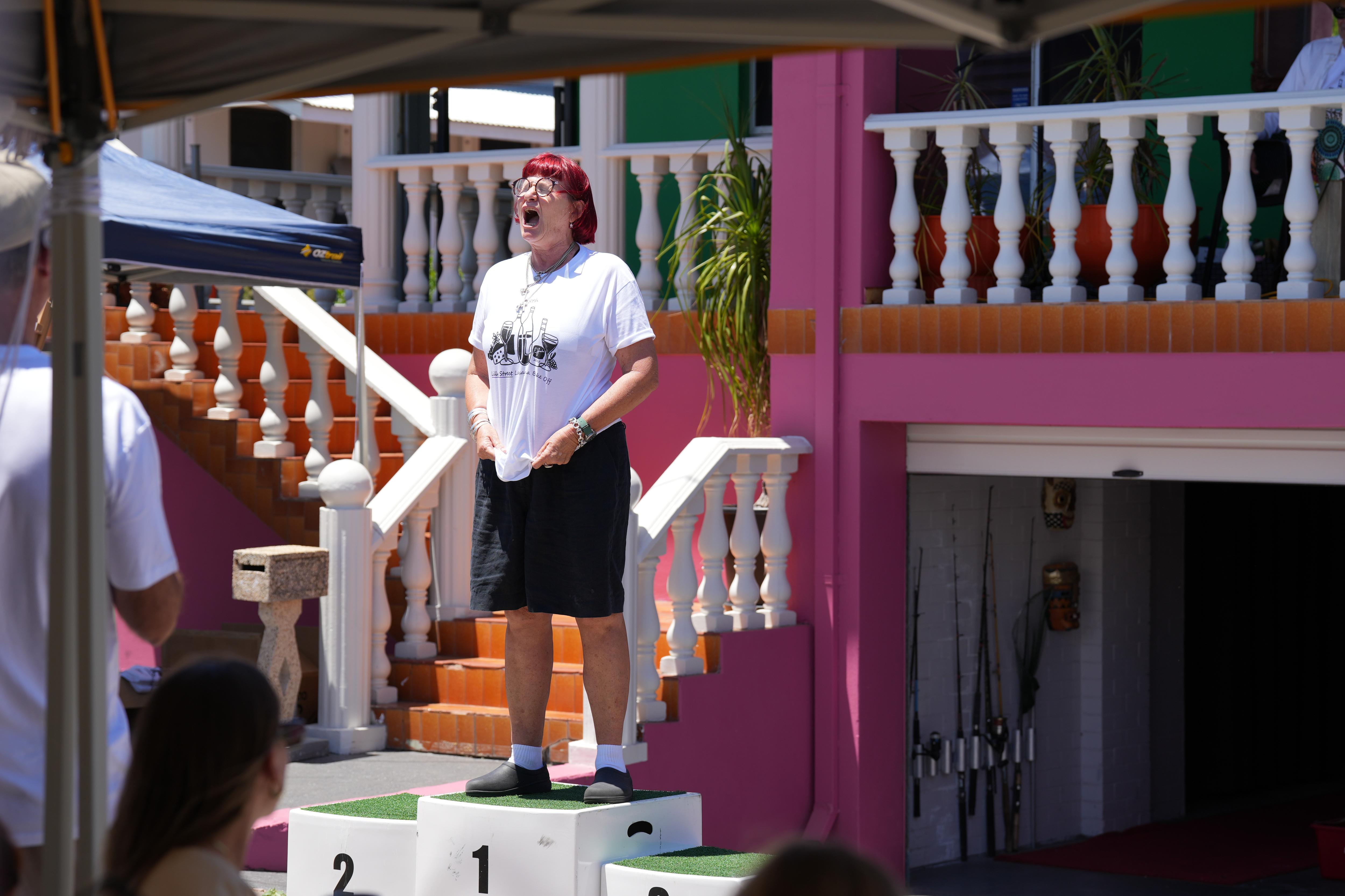     Jenny Baker se para en un podio y le grita a la multitud. 
