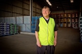 Lawrence Waterman stands in a warehouse stocked with bags of garden mulch and unused pallets.