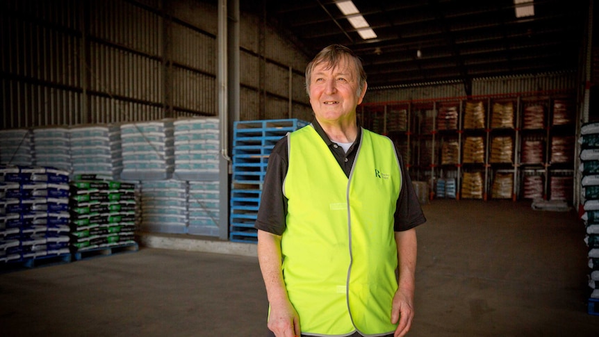 Lawrence Waterman stands in a warehouse stocked with bags of garden mulch and unused pallets.