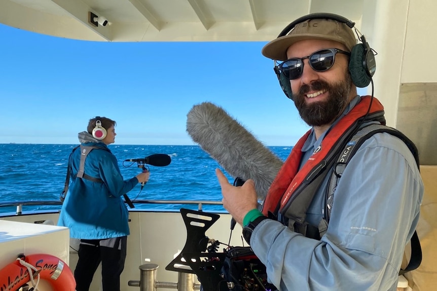 Man with headphones on and microphone on a boat.