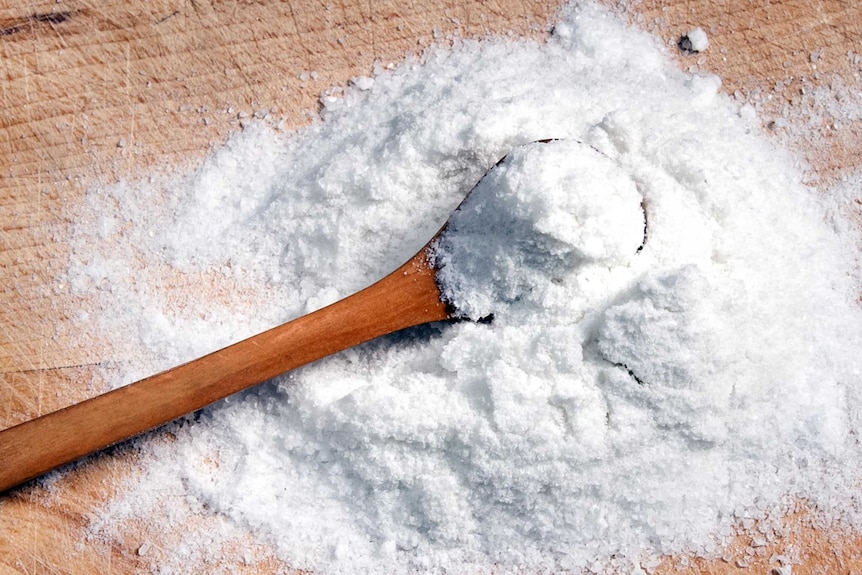 Spoon scooping salt on a bench.