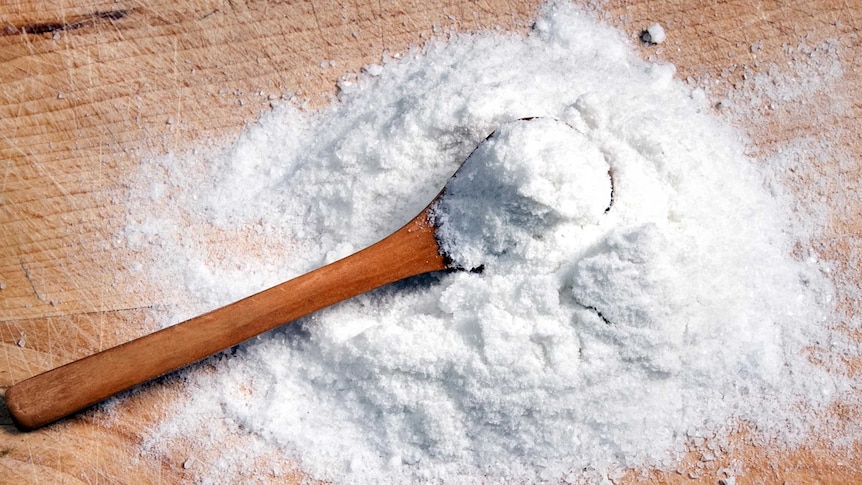 Spoon scooping salt on a bench.