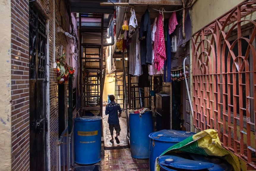 A man walks down an alleyway with washing hanging above him