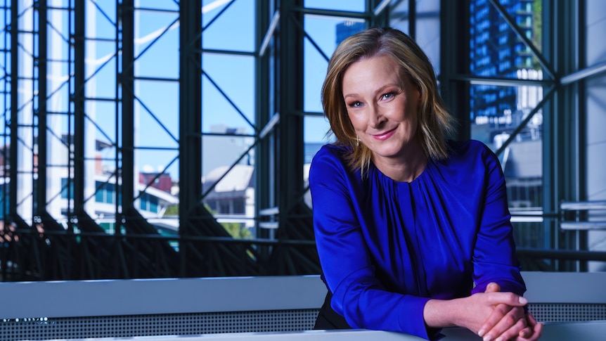 Leigh Sales in a blue sweater, smiling as she leans on a railing