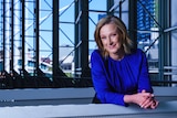 Leigh Sales in a blue sweater, smiling as she leans on a railing.