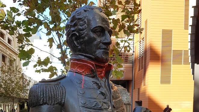A statue of Captain James Stirling with red spraypaint on his hands and around his neck.