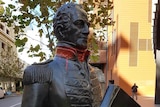 A statue of Captain James Stirling with red spraypaint on his hands and around his neck.
