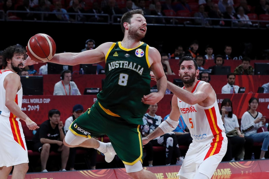 A male basketball players passes the ball one-handed.