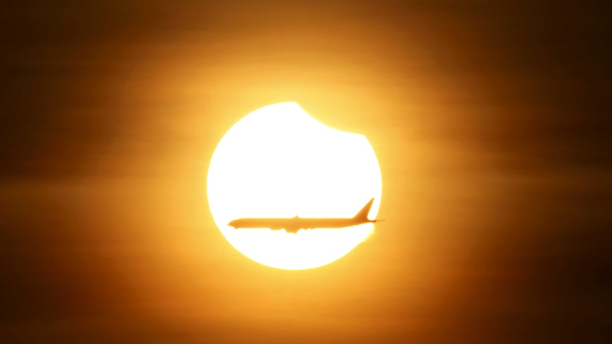 An aeroplane flies past the sun as it goes into a partial solar eclipse in Singapore.